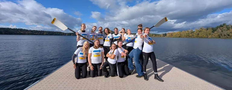 a team of rowers posing on a dock