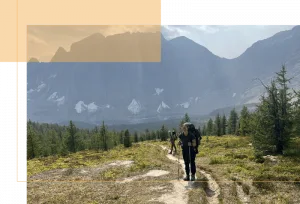 Deanna standing on a trail with mountains behind her
