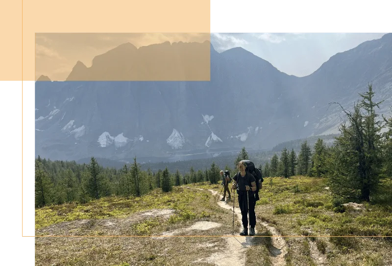 Deanna standing on a trail with mountains behind her