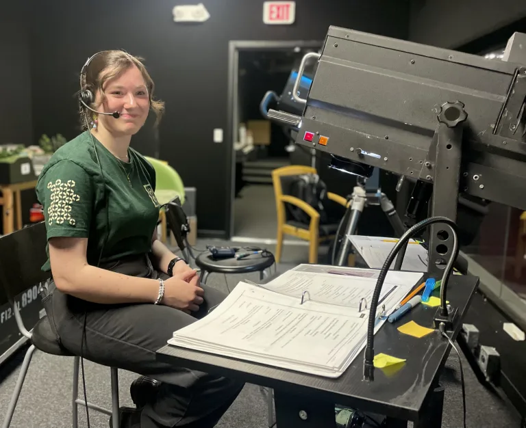 A girl in a green HCOS shirt operating stage lights