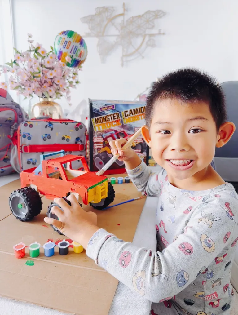 a boy painting a cardboard monster truck