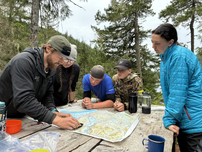 a group of people around a table looking at a map in a forest