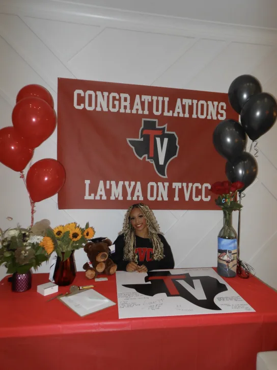 La'Mya sitting at a table with a banner behind her stating congratulations