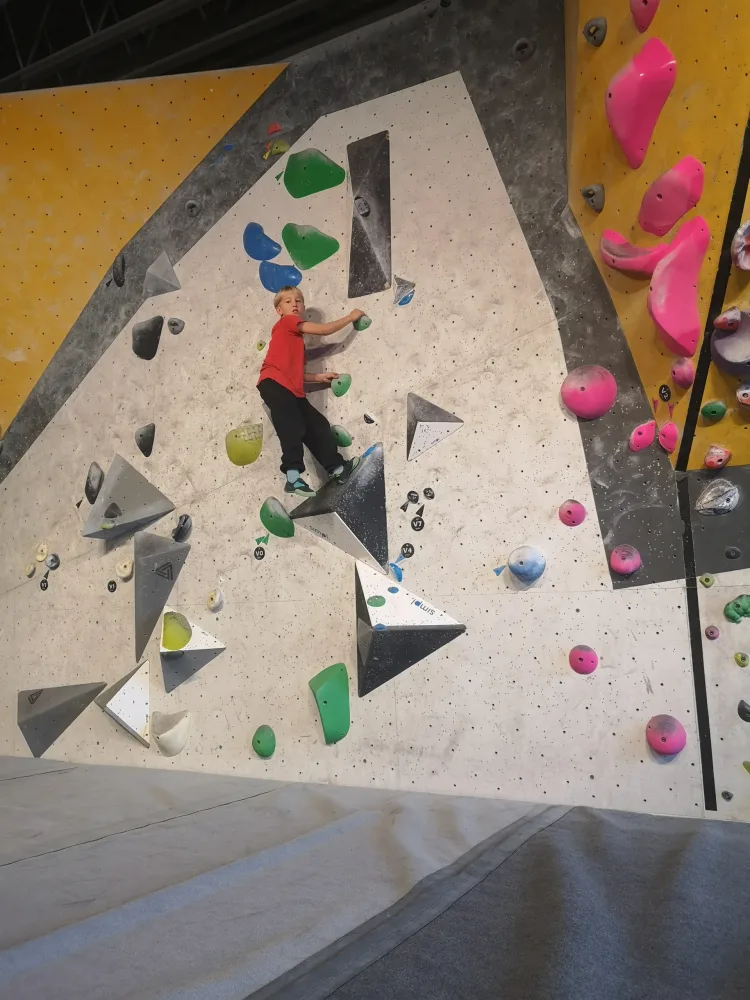Nathaniel climbing a wall and looking at the camera