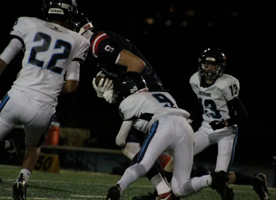 a football player in a white jersey tackling another player on the opposing team