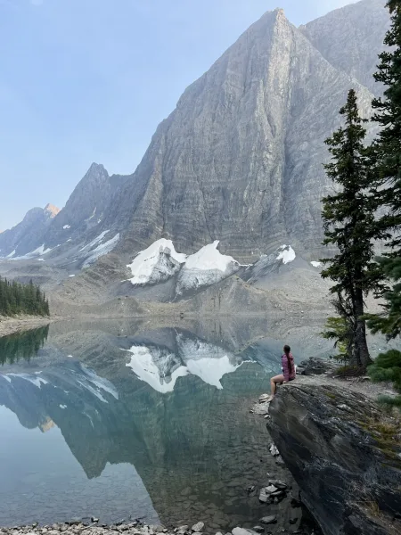 Deanna sitting on a rock in front of a mountain lake scene